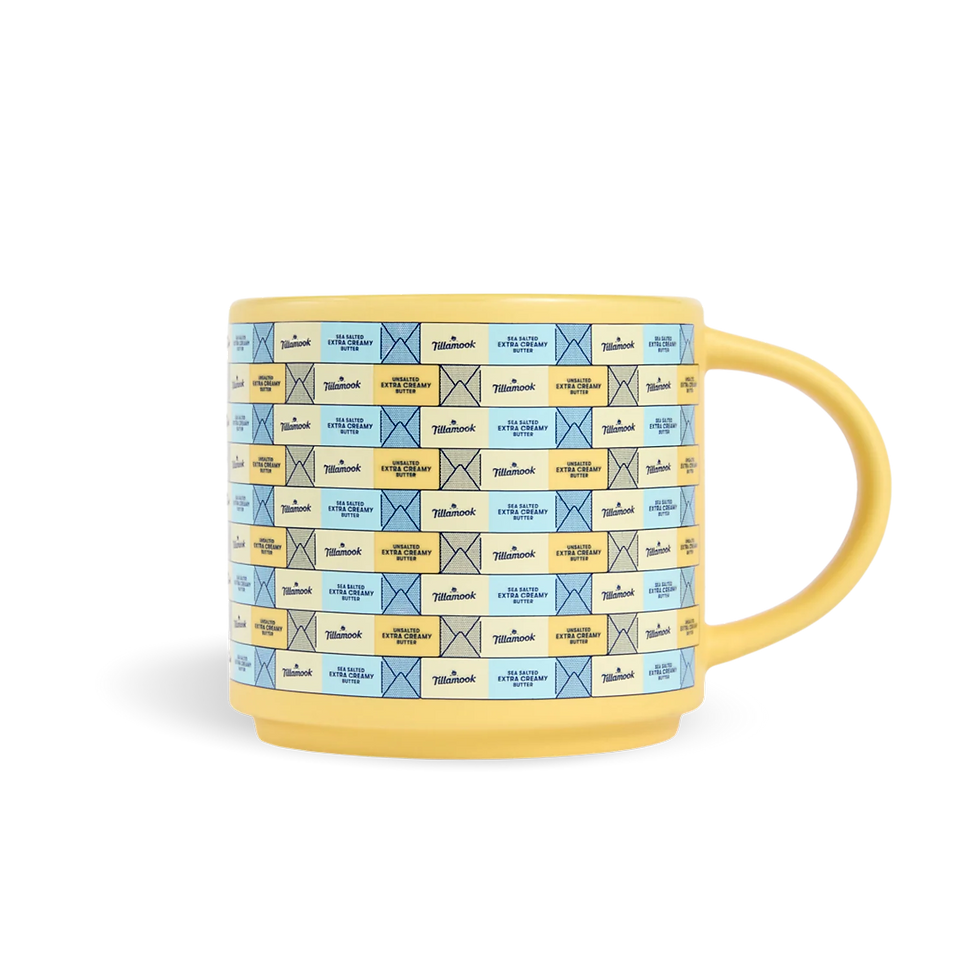 Yellow mug with Tillamook sea salted and unsalted extra creamy butter labels on a black background.