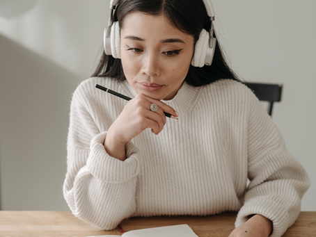 Small business owner wearing headphones while reviewing customer support notes at a desk