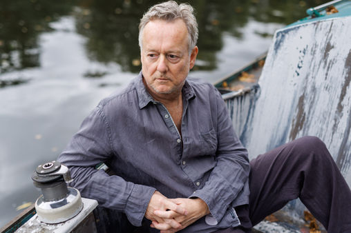 Portrait of British/German actor Ian Dickinson sitting on a small boat on the Görlitzer Ufer, Kreuzberg, Berlin 2024