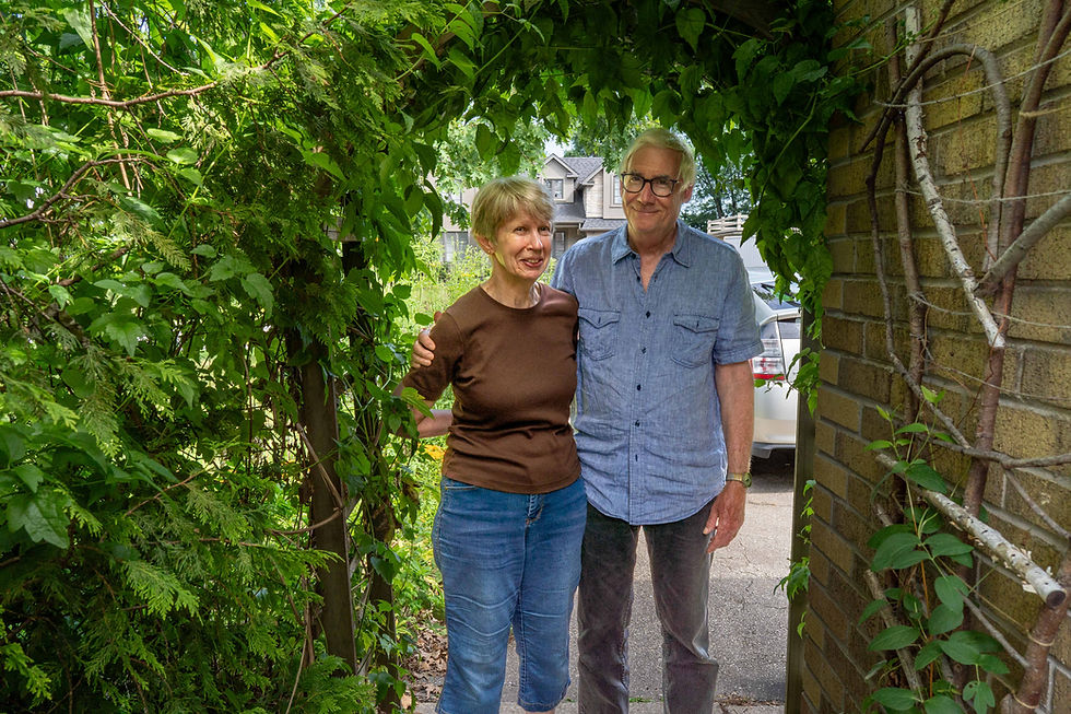 A couple standing under a vine-covered archway.