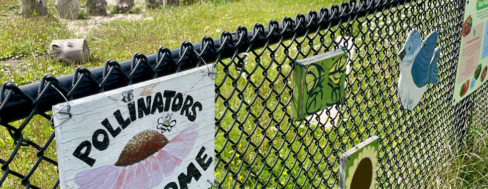 Pollinators welcome sign on chain link fence
