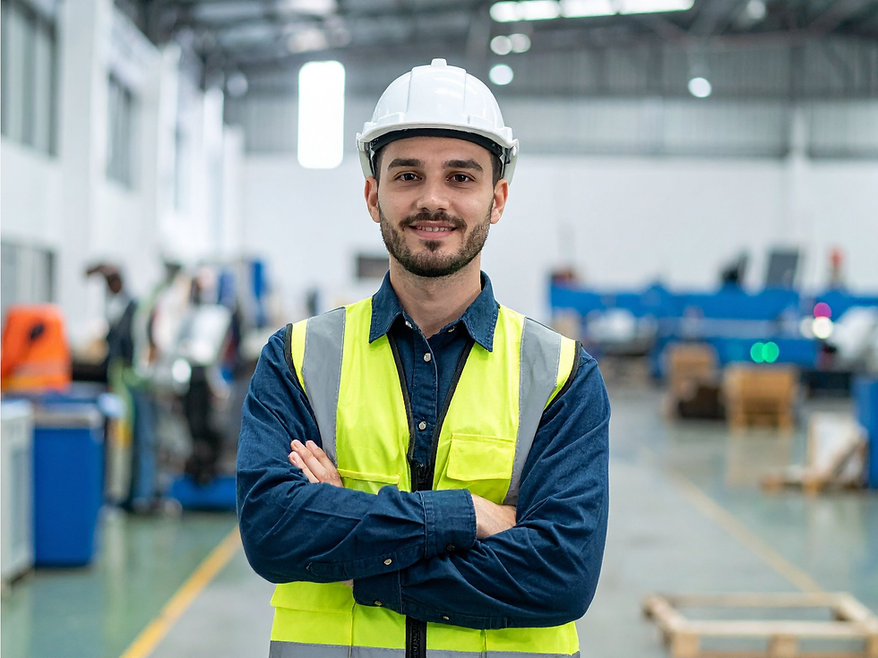 Trabajador industrial con casco y chaleco de seguridad dentro de una planta de manufactura.