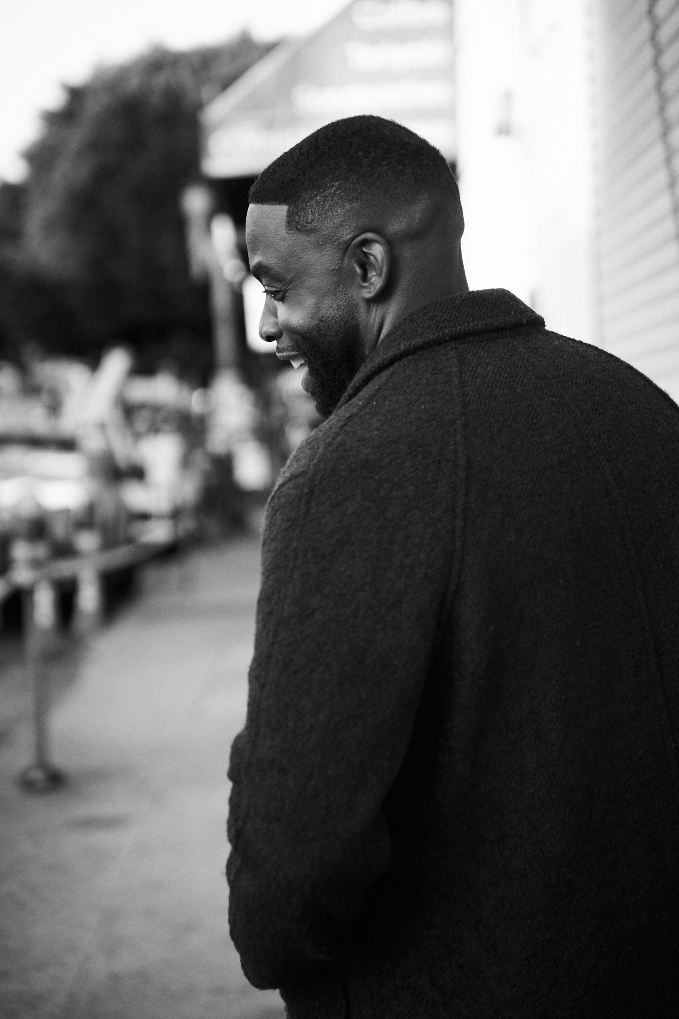 Thomas Copeland Jr. smiling over his shoulder in a black-and-white street portrait