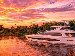 Lancha de luxo navegando no pantanal, ao pôr do sol.