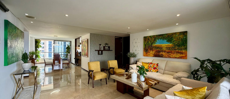 Sala principal amoblada con sofás claros y gran ventanal con vista a Medellín, Guayacanes La Calera