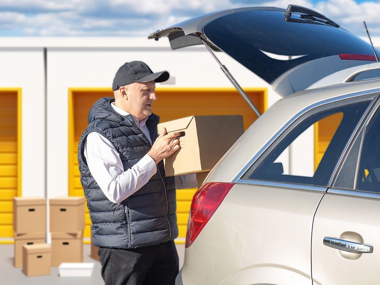 Man takes boxes from storage units. Guy puts packages into car. Man with boxes near storag