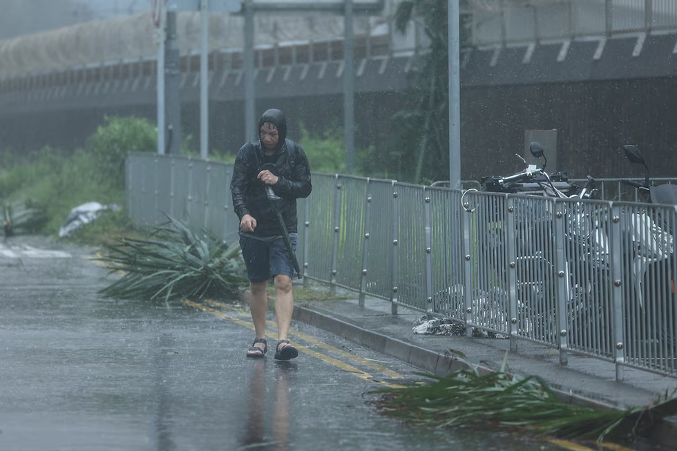 A man walks amid rain as Typhoon Wipha approaches, in Hong Kong, China, July 20, 2025. REUTERS/Tyrone Siu