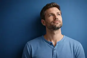 A person thoughtfully reflecting on the question “Who is Jesus?” against a solid blue background.