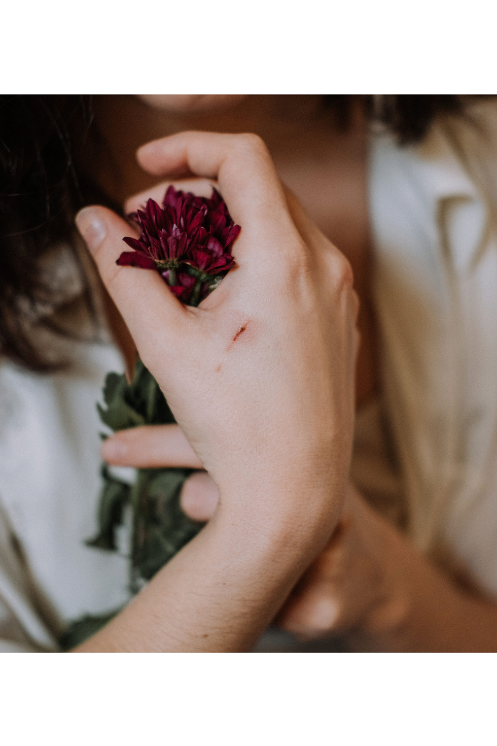 Hand holding a small red flower, a faint scratch across the hand — chronic irritability blog, Myriad Therapy