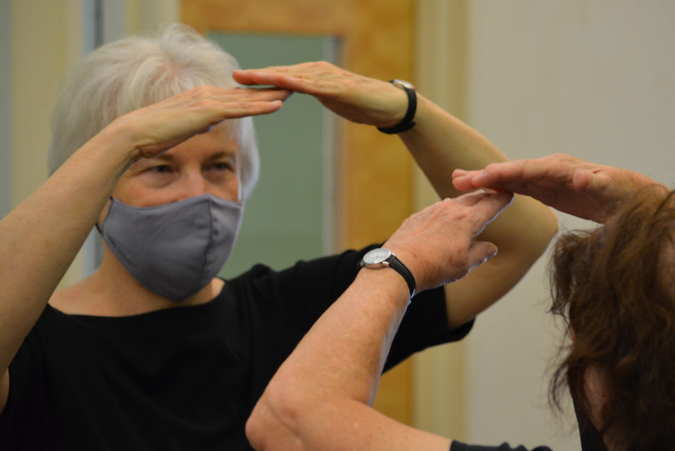 An older woman practicing movement in a class.