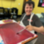 A woman is painting a canvas red while smiling.