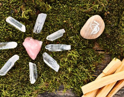 an image of crystals laid out in a grid with palo santo sticks laid out next to the grid