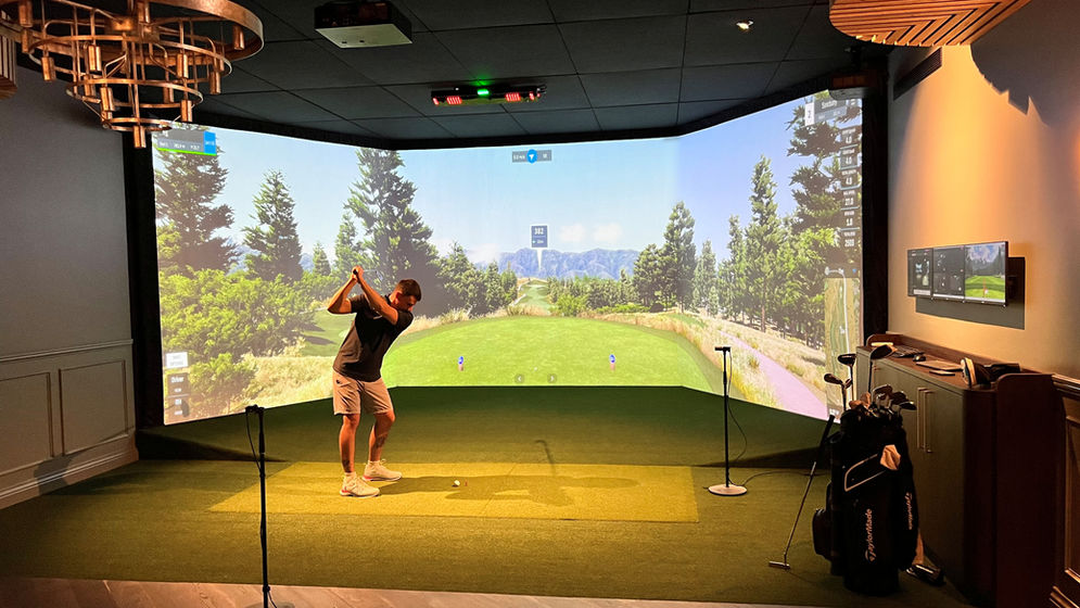 Golfer mid-swing inside luxury home golf simulator powered by GSPro and Uneekor, surrounded by high-end furnishings and launch data on screen.