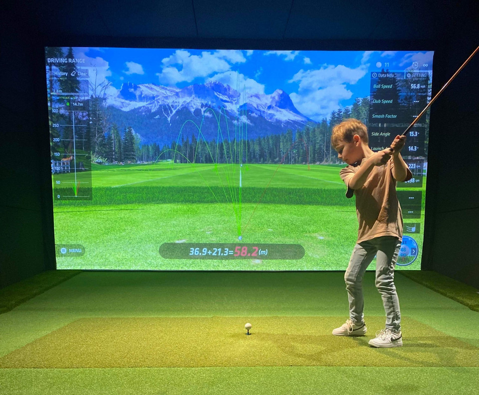 Child playing on indoor golf simulator with realistic course visuals and training mode active — family-friendly install by Golfsim Australia.