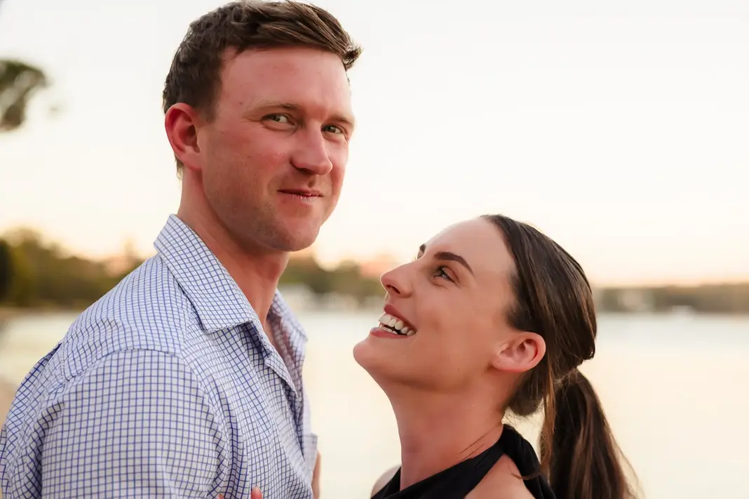 Baleigh smiling up at Kailym while he looks at the camera during their engagement session at Matilda Bay Reserve.