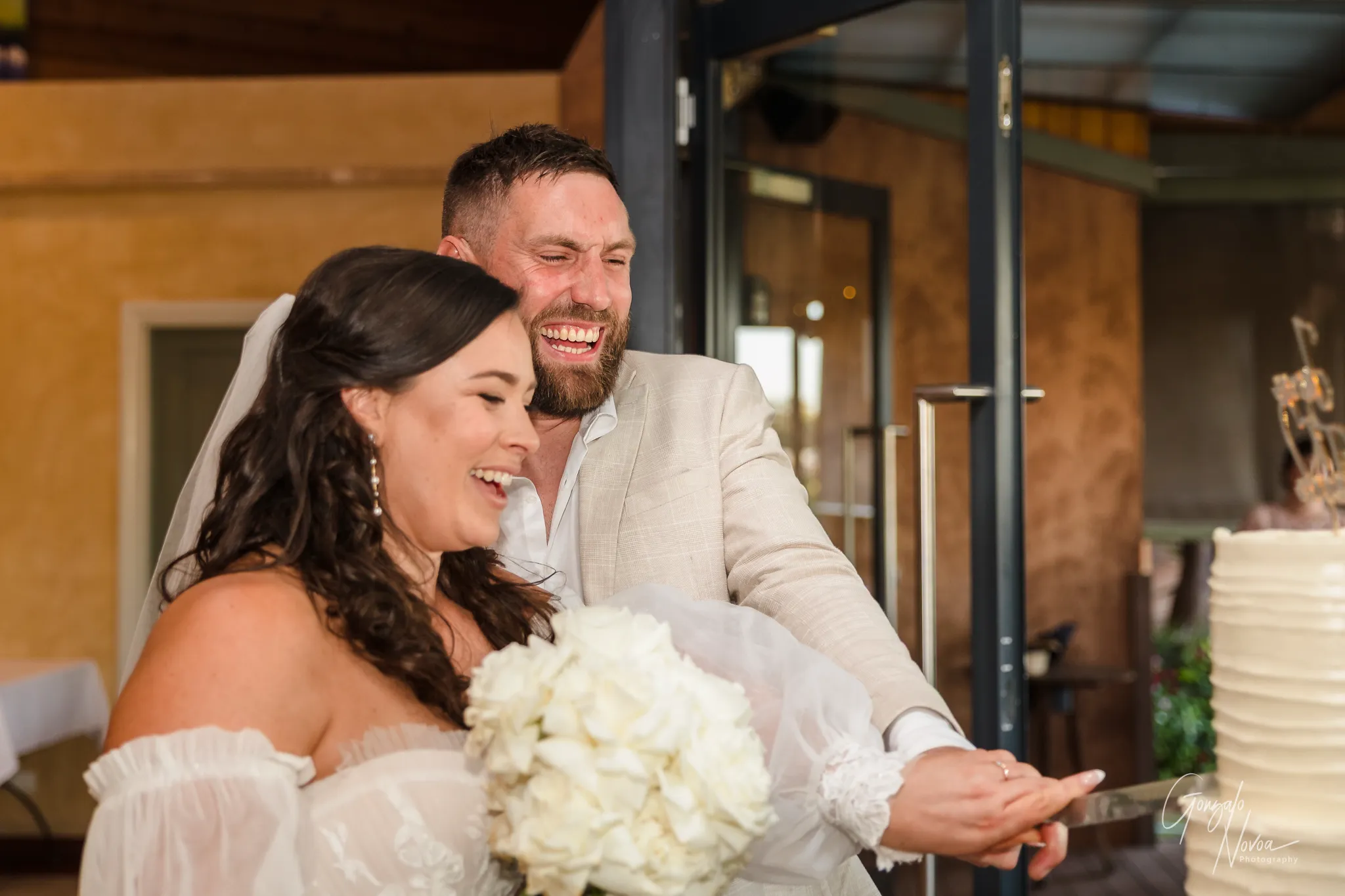 Bride and groom laughing joyfully as they cut their wedding cake together