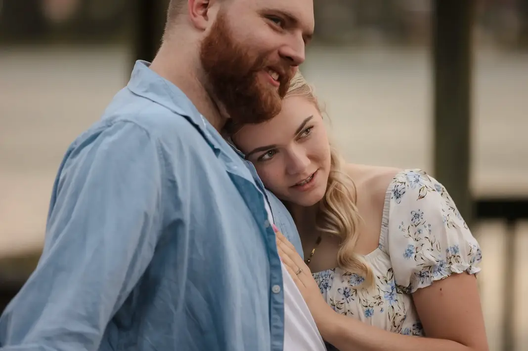 Close-up of Faith resting her head on Alex’s shoulder during their engagement shoot at Lake Monger, with soft natural light and visible engagement ring.