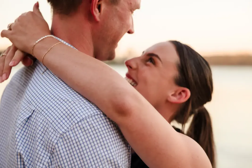Close-up of Baleigh smiling up at Kailym with her arms wrapped around his shoulders during their engagement session at Matilda Bay Reserve.