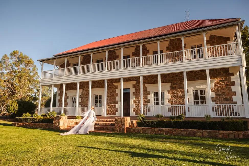Bride walking up the steps toward Buckland Estate in WA, with her veil trailing behind her.