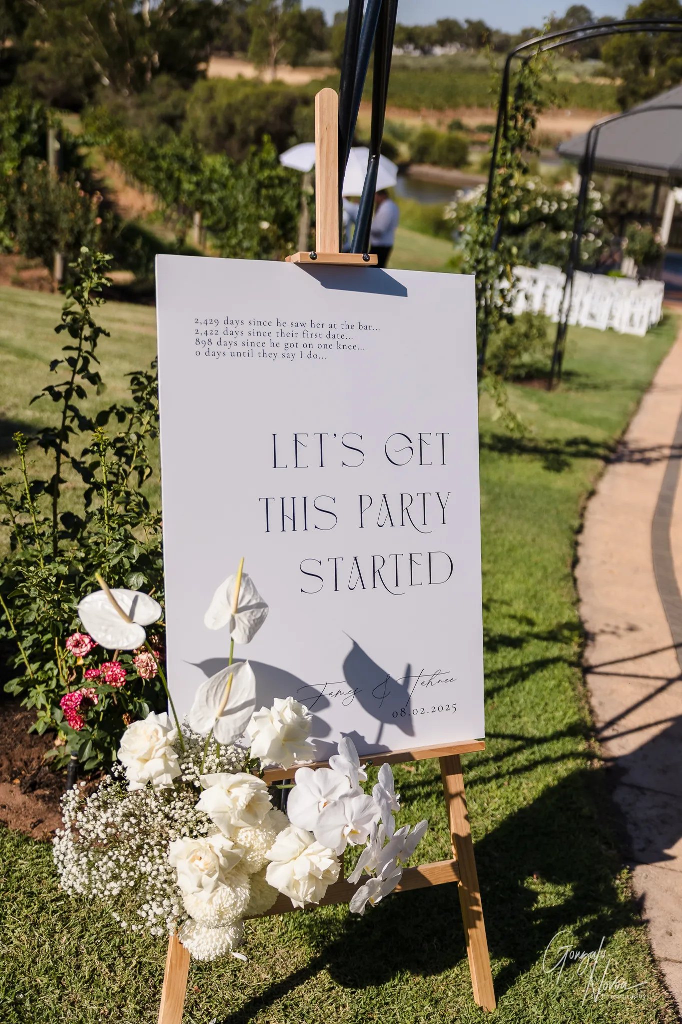 Wedding welcome sign at Sittella Winery reading “Let’s Get This Party Started,” with white flowers.
