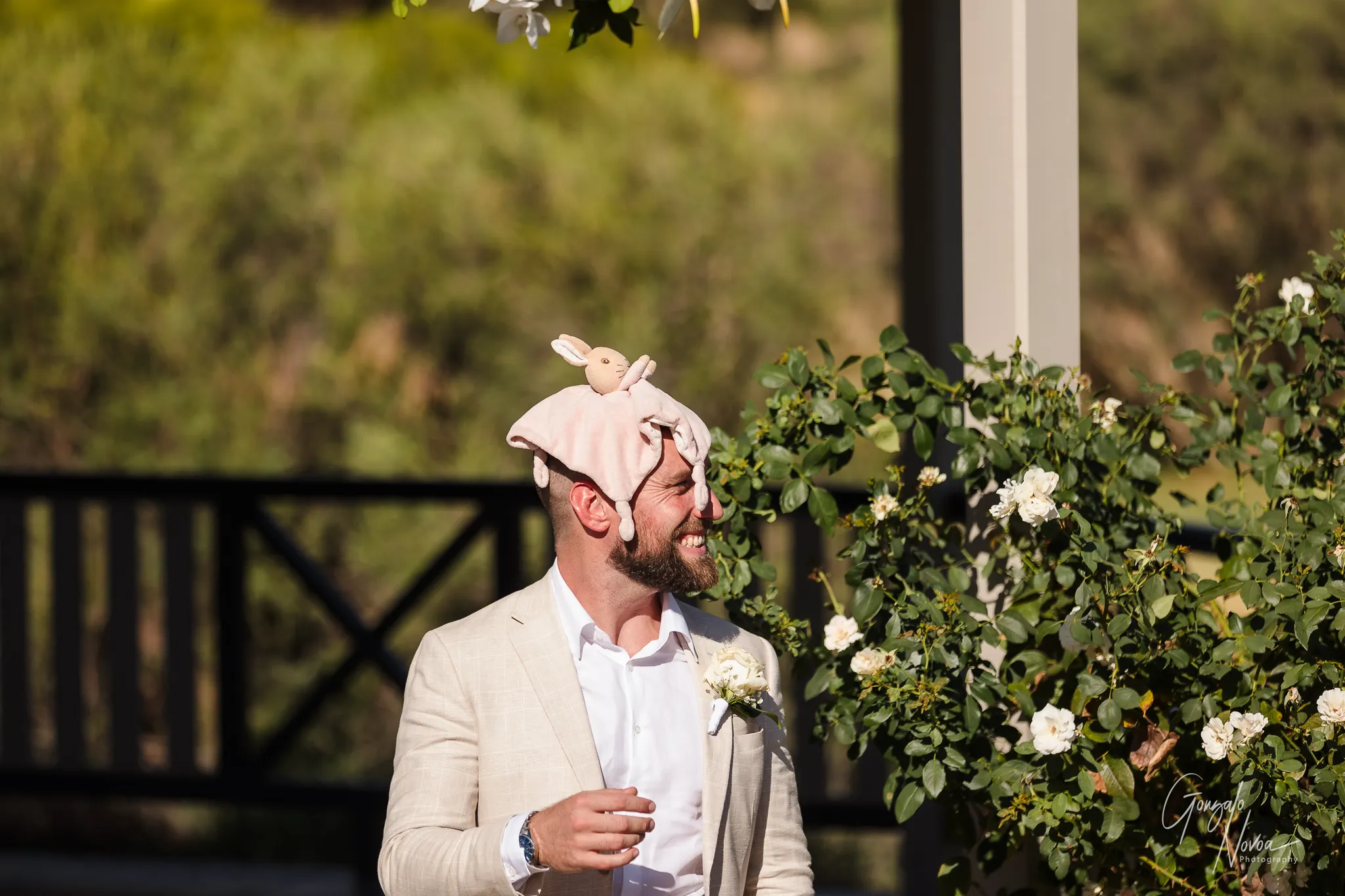 Groom laughing while wearing a soft toy bunny hat during the wedding ceremony setup at Sittella Winery.