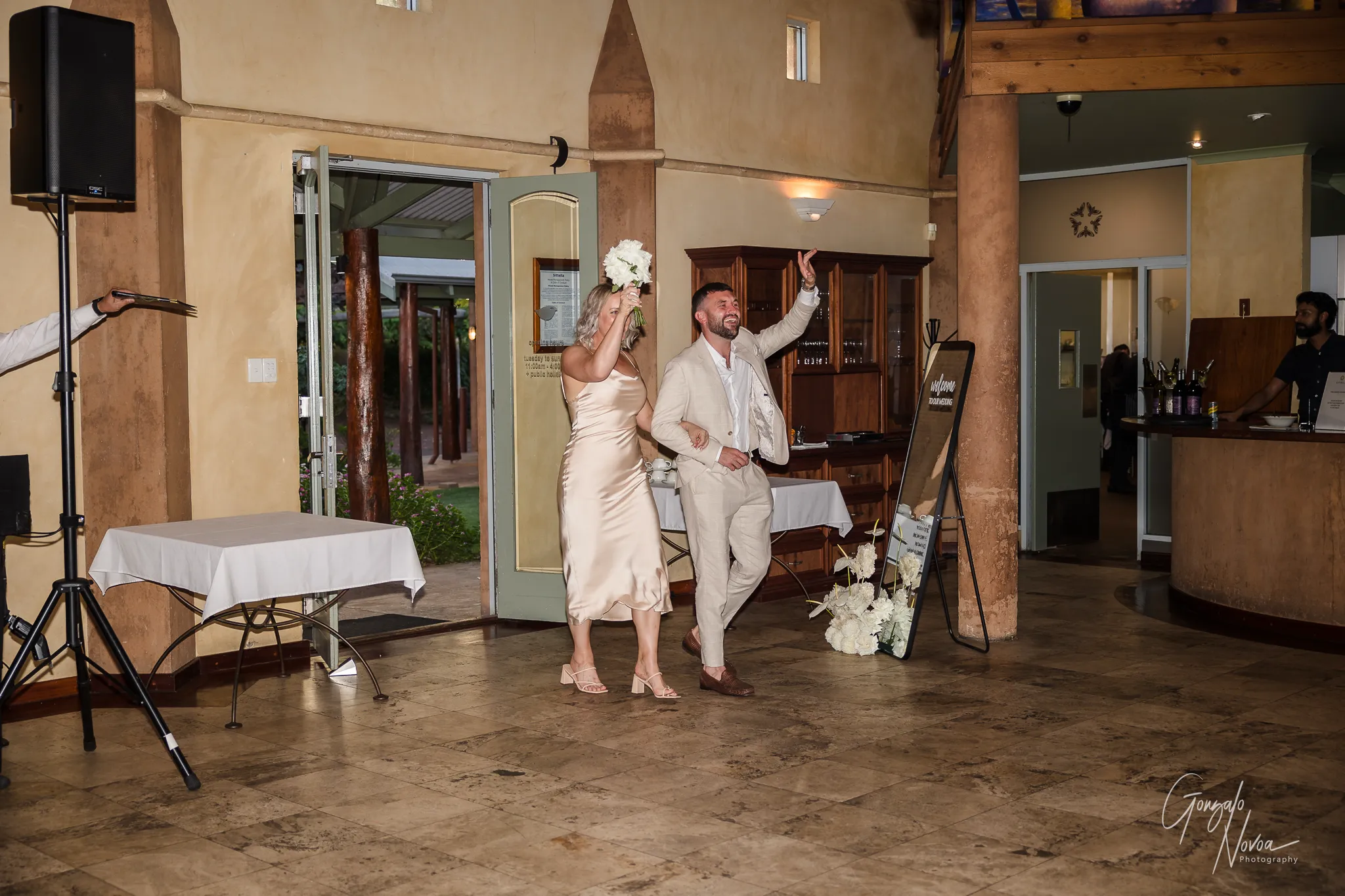 Bridesmaid and groomsman walking into the reception, laughing and waving excitedly