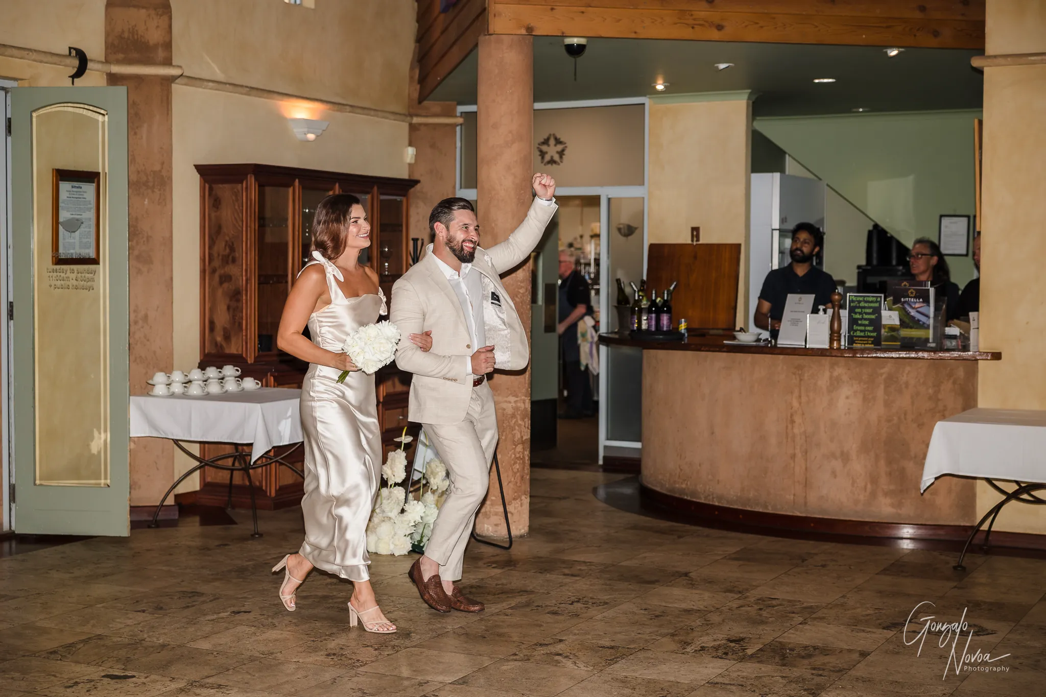 Bridesmaid and groomsman making a fun entrance into the reception, smiling and celebrating with raised arms
