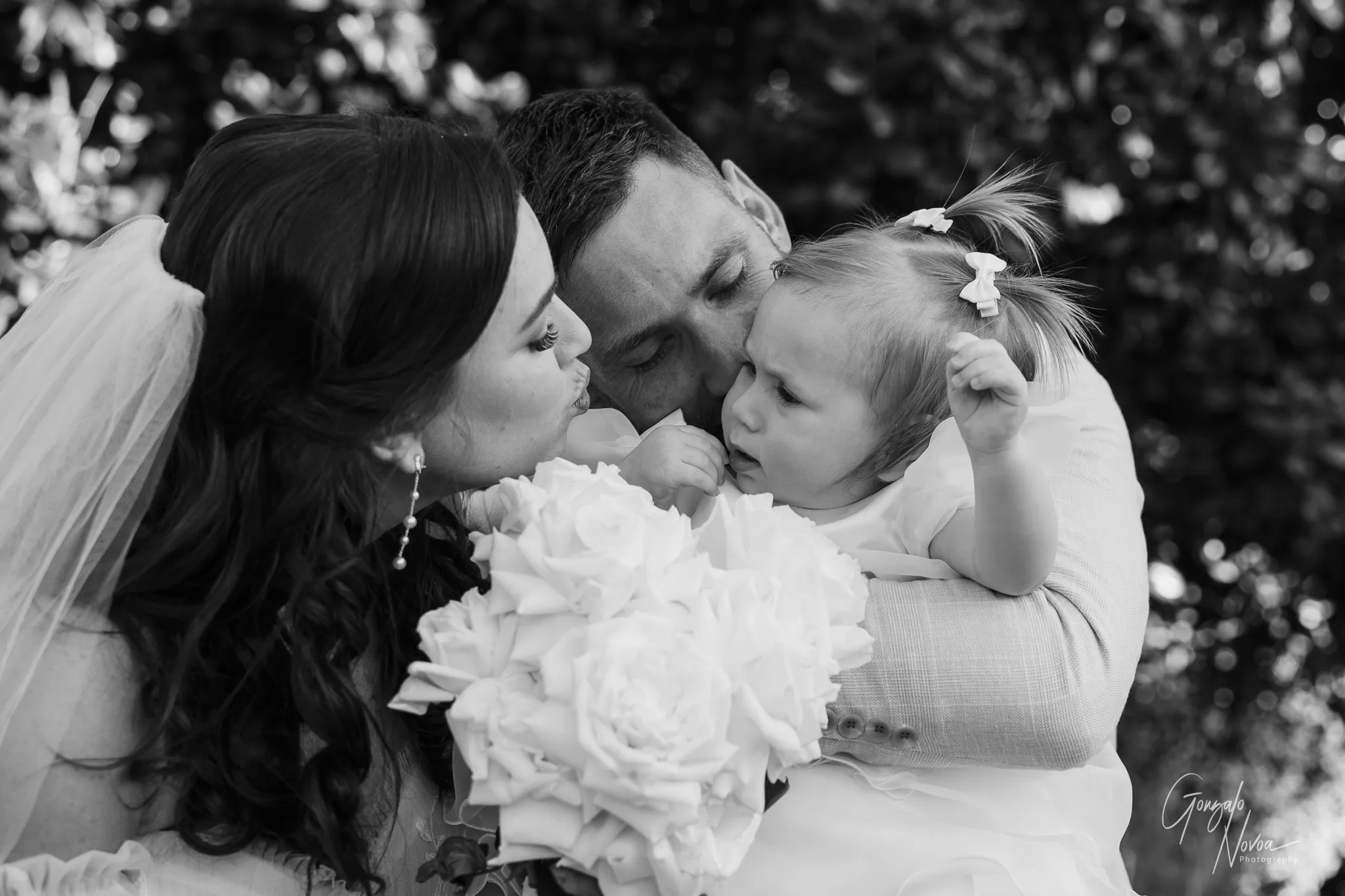 Black and white close-up of Tahnee and James giving baby Arlea sweet kisses during their wedding day