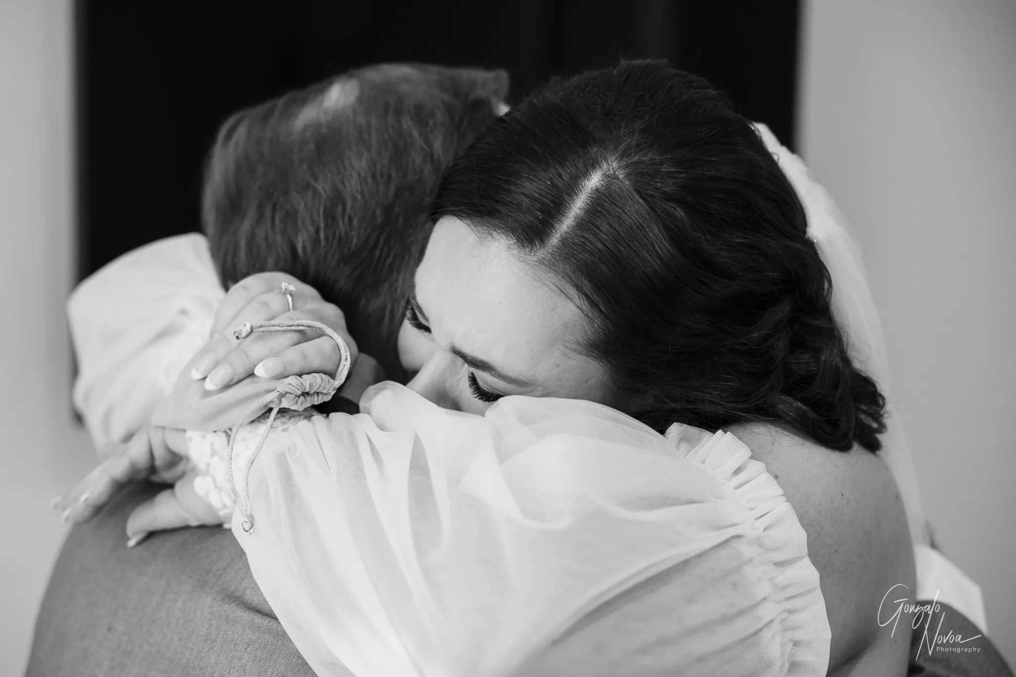 Black and white close-up of bride Tahnee hugging her dad tightly, moments after gifting him a personalised handkerchief before the wedding ceremony.
