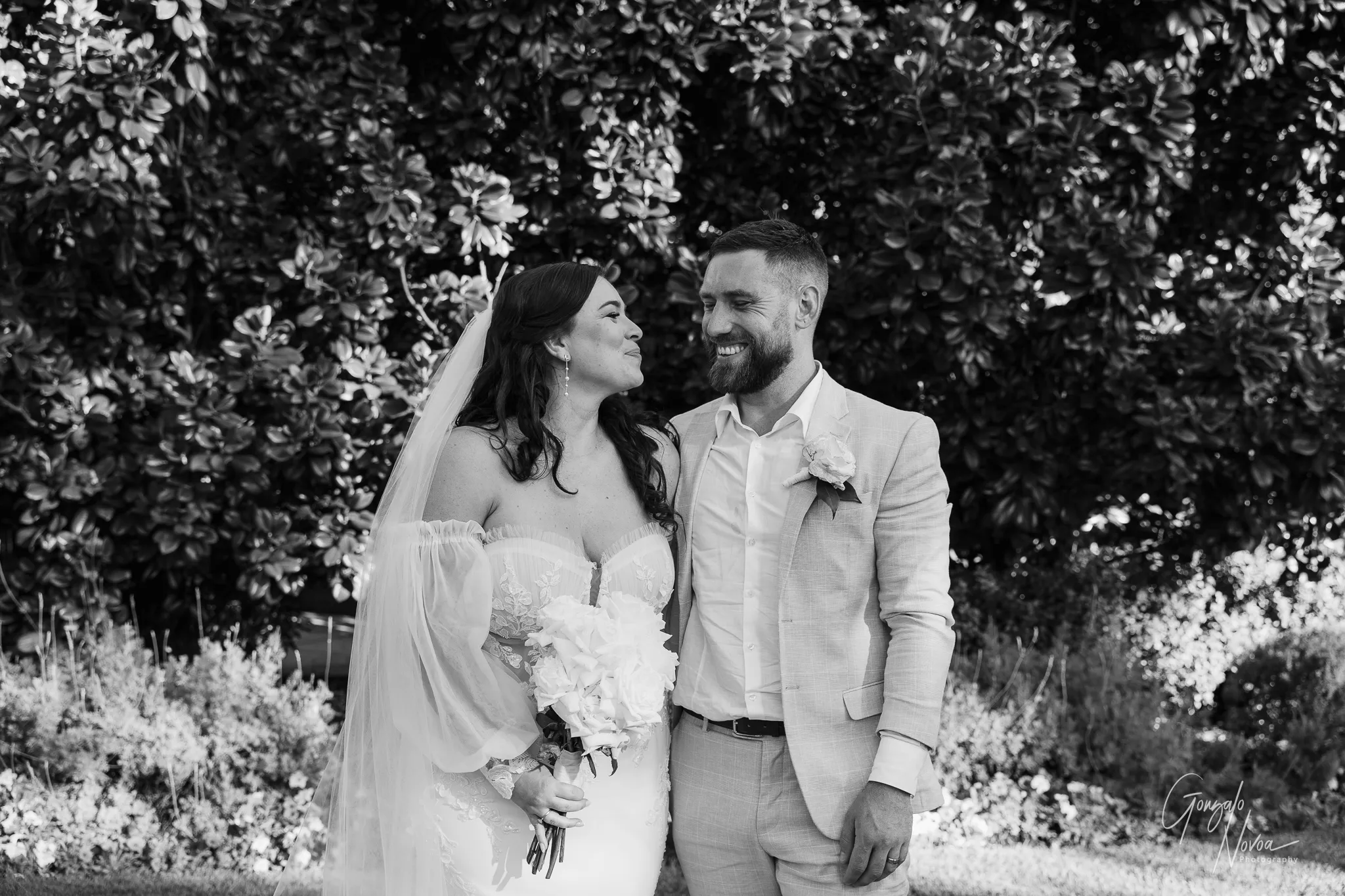 Black and white photo of Tahnee and James smiling warmly at each other, standing close together after their ceremony