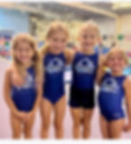 four little girl gymnasts smiling and wearing blue leotards that say Tumbleweeds
