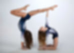 two female gymnasts posing together with one in a handstand and one leaning back