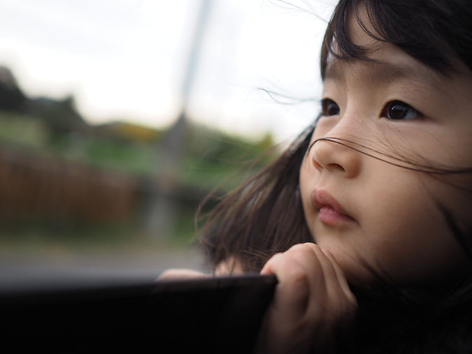 Una bambina asiatica in primo piano di lato, con espressione neutra, che sembra guardare lontano, rappresentando la contemplazione e la vulnerabilità nei disturbi d'ansi