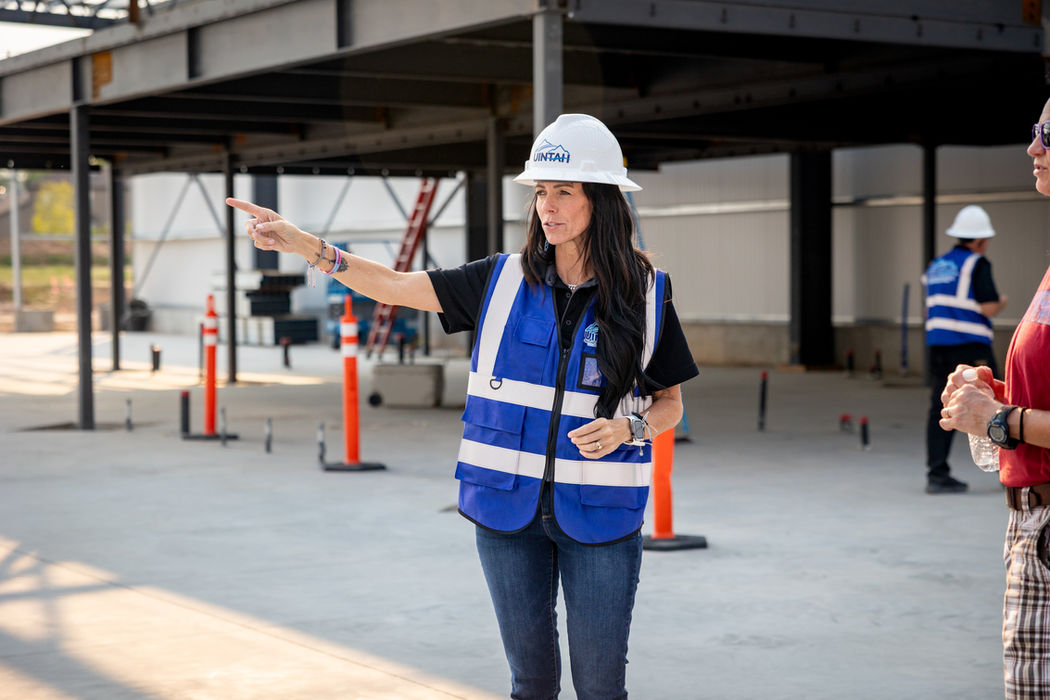 Woman in hard hat and safety vest pointing during site tour