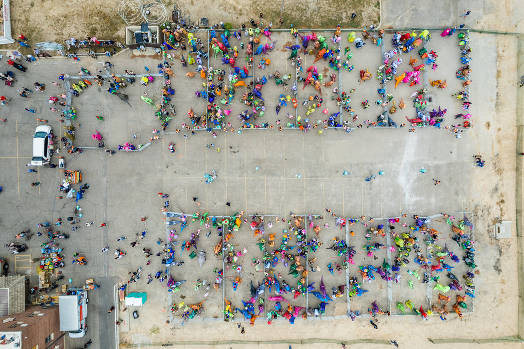 Aerial view of a costumed crowd spread across a parking lot in smaller clusters