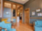 A small lounge area with lots of light wood paneling and floor. Blue lounge chairs are in the forground.