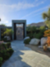 View of house entrance with gray lace-like doors at the end of a path.