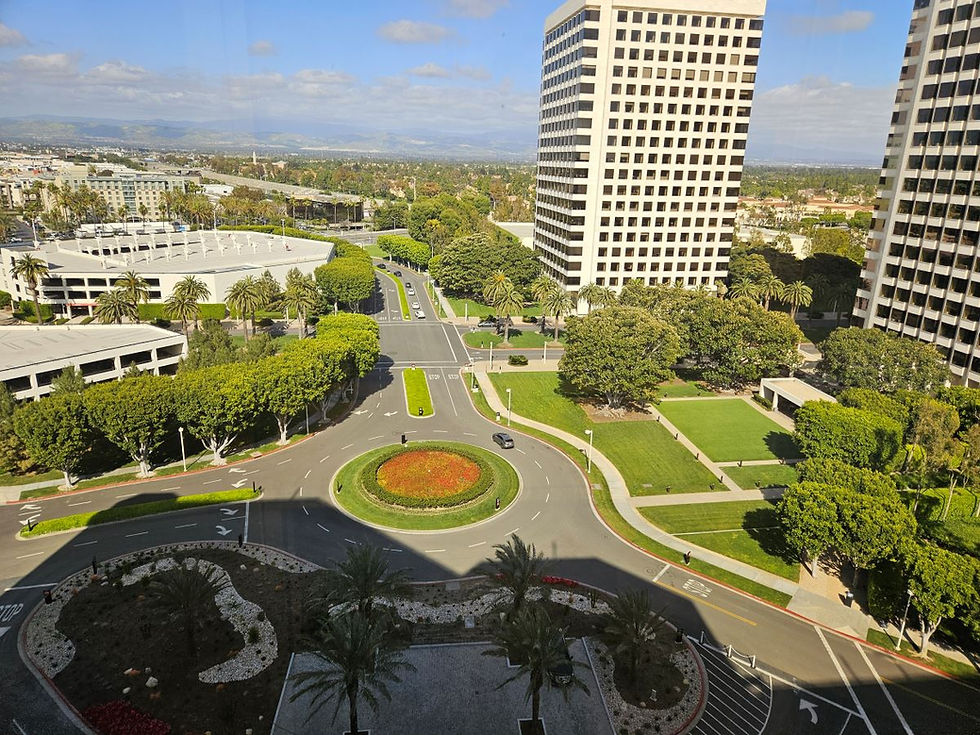 View of distance buildings taken from the Hyatt Regency Irvine Glass Elevator. Shows large circle for traffic with flowers in the center.