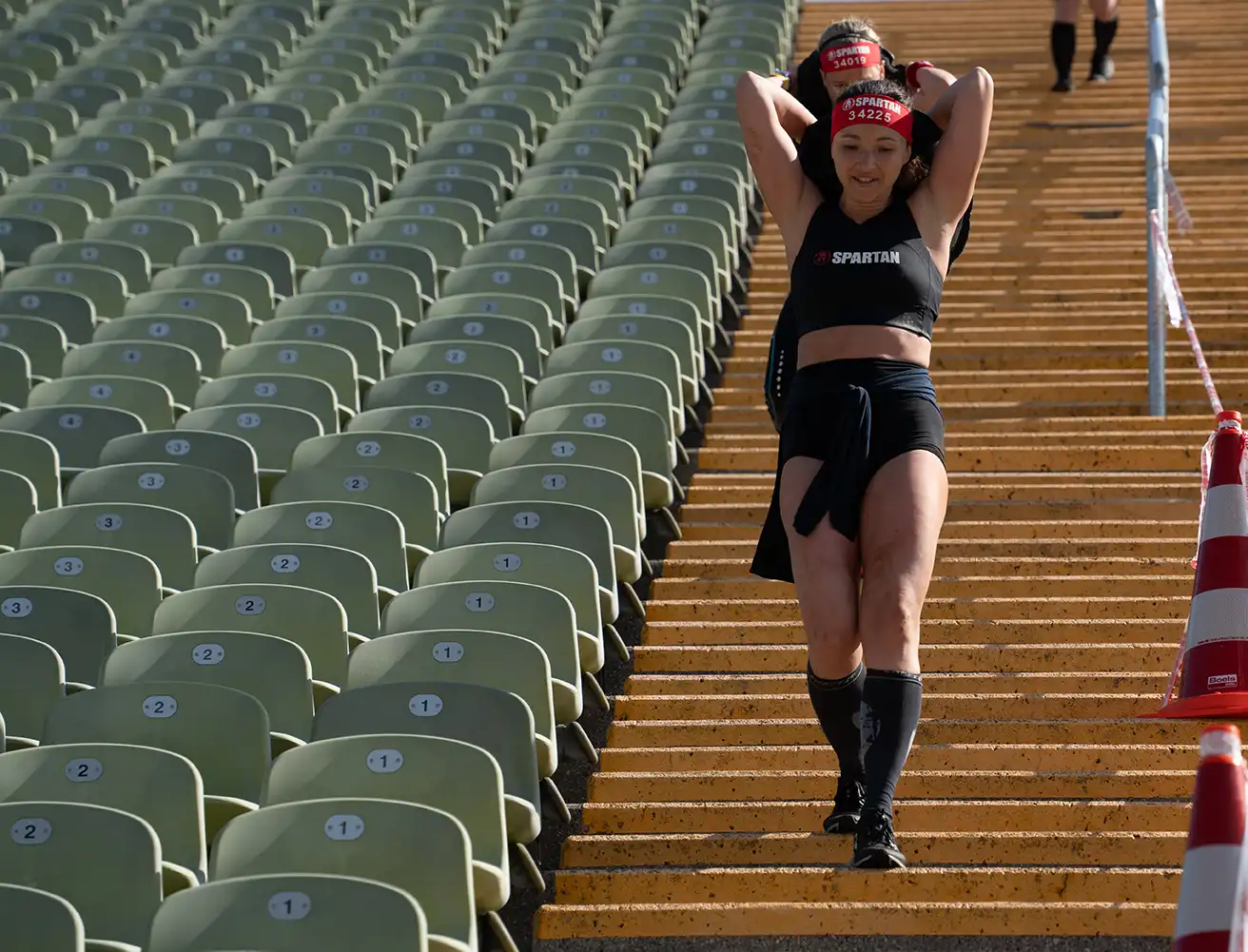 Woman carries a heavy sandbag up the Olympic Stadium stairs