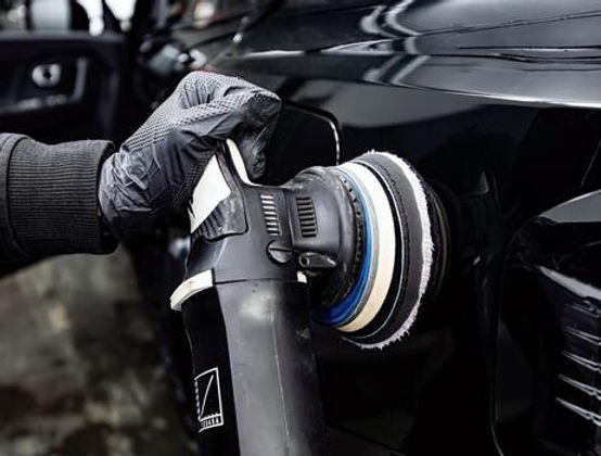 man-with-orbital-polisher-polishing-car-in-detailing-center-photo.jpg