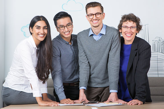 four-smiling-business-people-standing-table.jpg