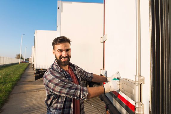 smiling-truck-driver-working-gloves-opening-closing-truck-trailer-back-doors-checking-good