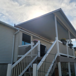 A tall elevated roof mount awning attached to the building's roof allowing the roof to extend naturally into the patio covering allowing shade from a higher vantage point.
