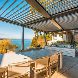 A beautiful waterfront home with a louvered awning covering the back patio with adjustable slats that control the coverage of the awning.