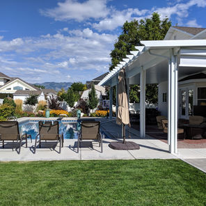 A stylish white outdoor awning in the Newport Style built by Utah Awnings to cover a poolside seating area.