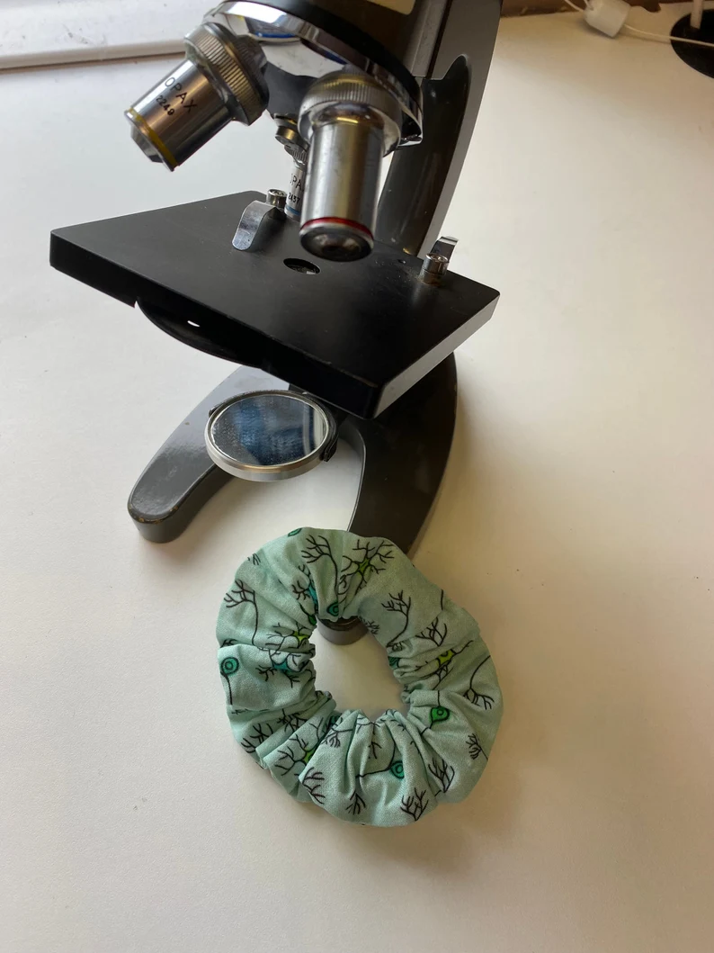 A green scrunchie with a neuron pattern, next to a microscope