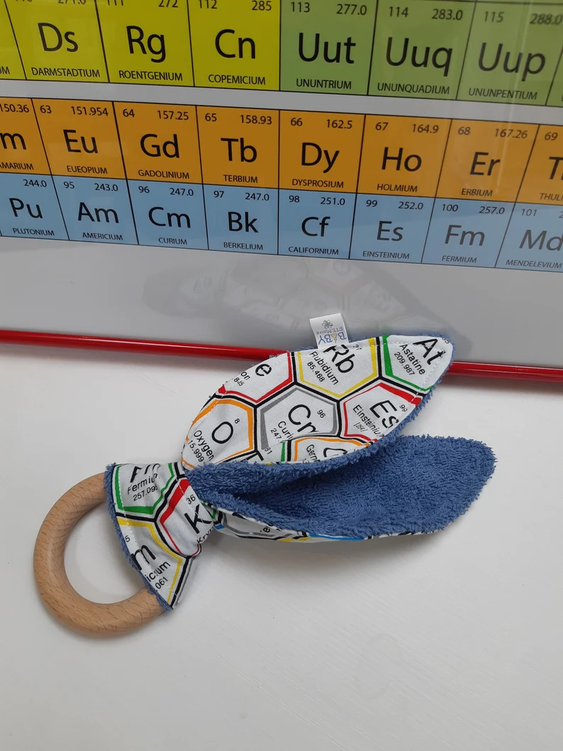 A wooden teething ring with fabric covered in the periodic table