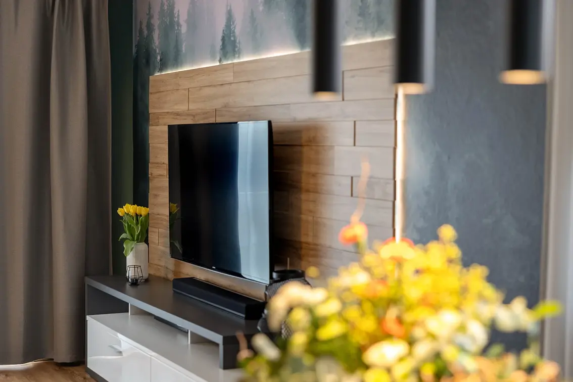 TV-Wand mit Holzpaneelen hinterleuchtet mit Waldtapete