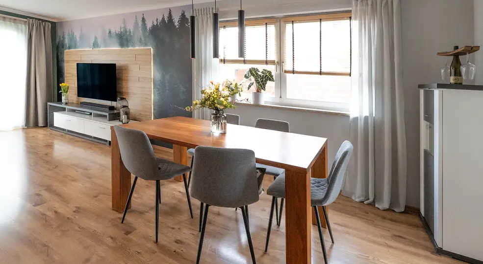 TV-Wand mit Holzpaneelen und Waldtapete und Essbereich