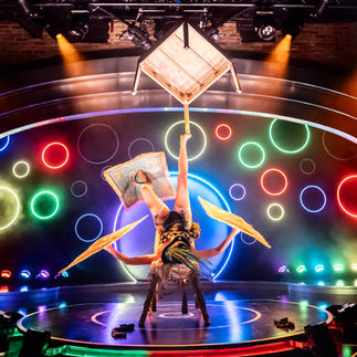 A woman performs on stage, balancing a chair on her foot